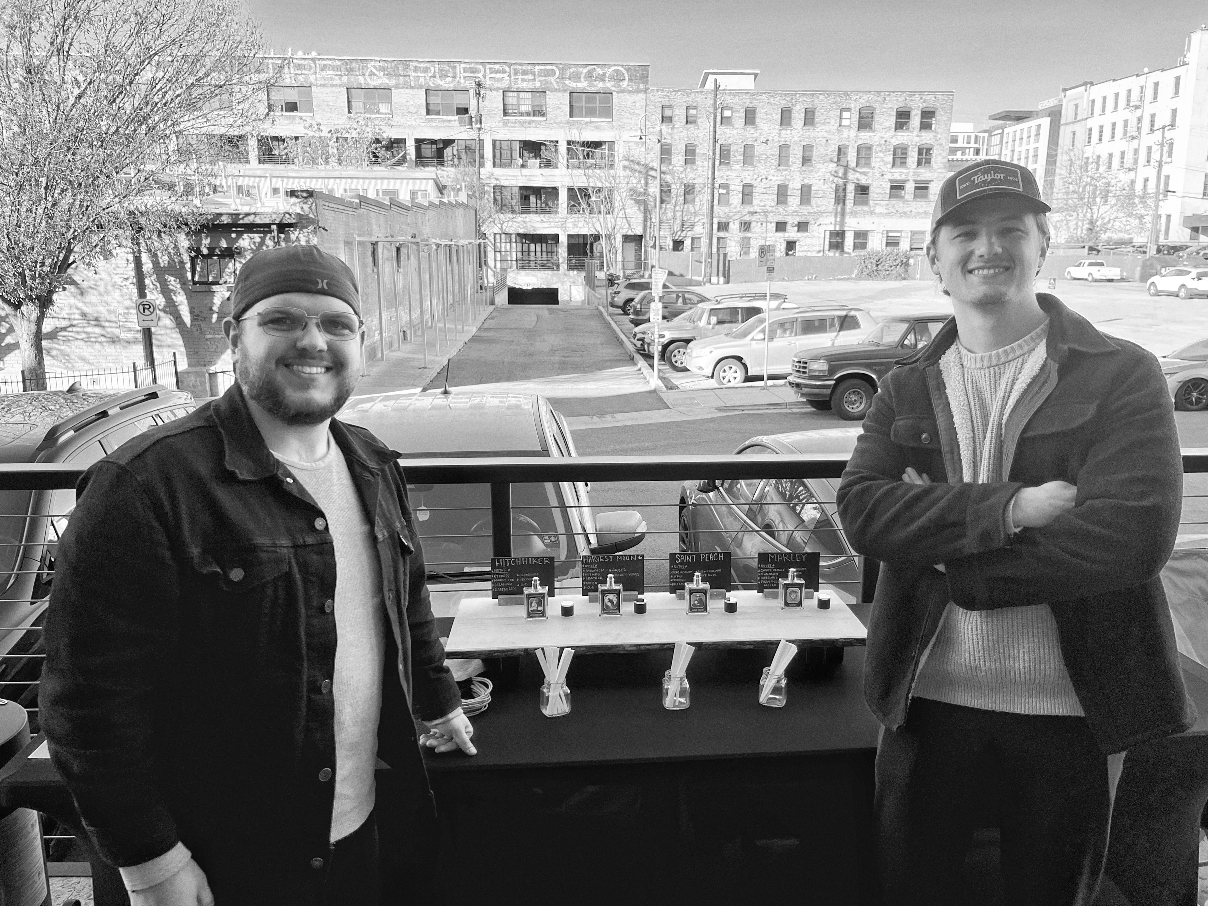 Two men standing on a rooftop with a cityscape in the background