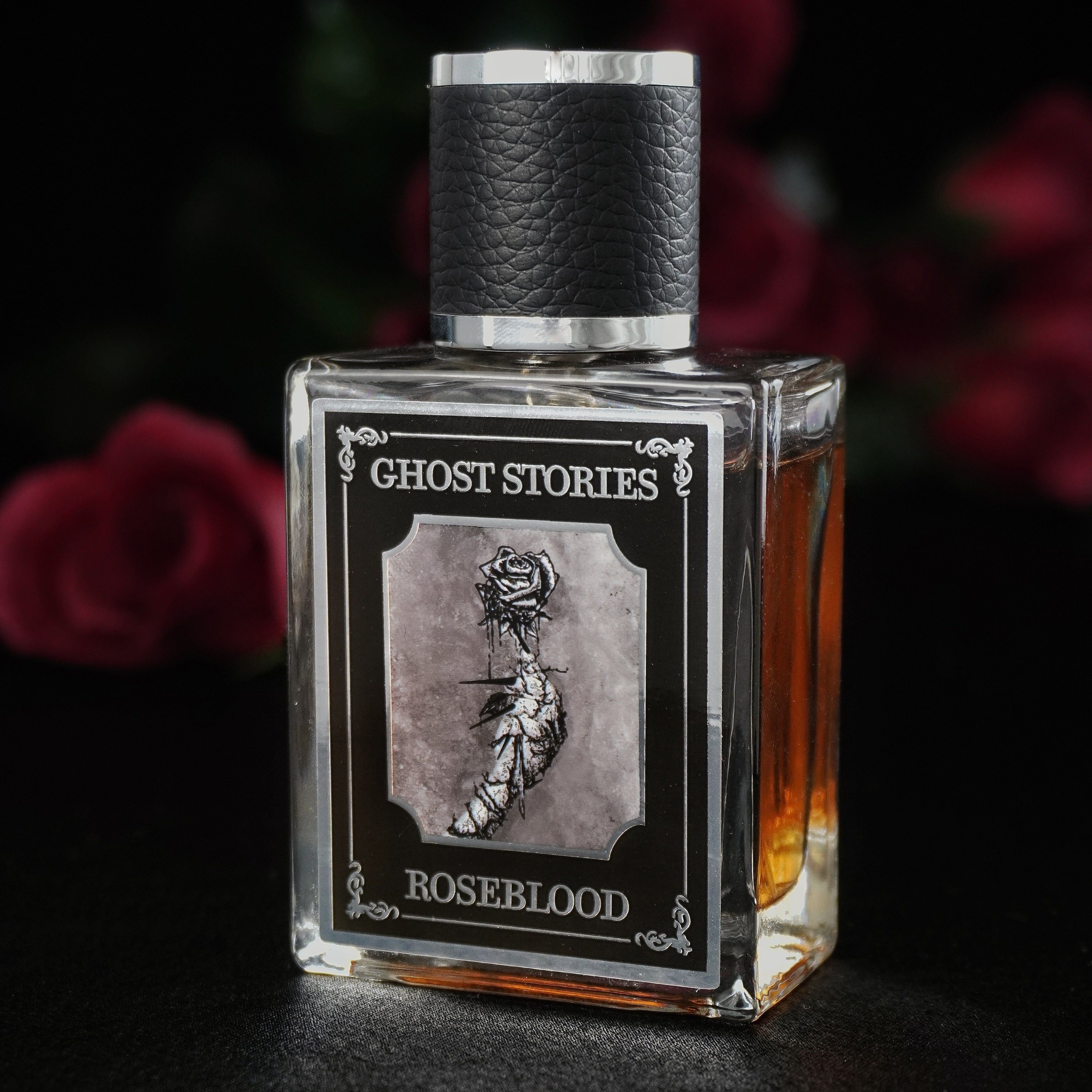 Perfume bottle labeled 'Ghost Stories Roseblood' with a dark background and roses