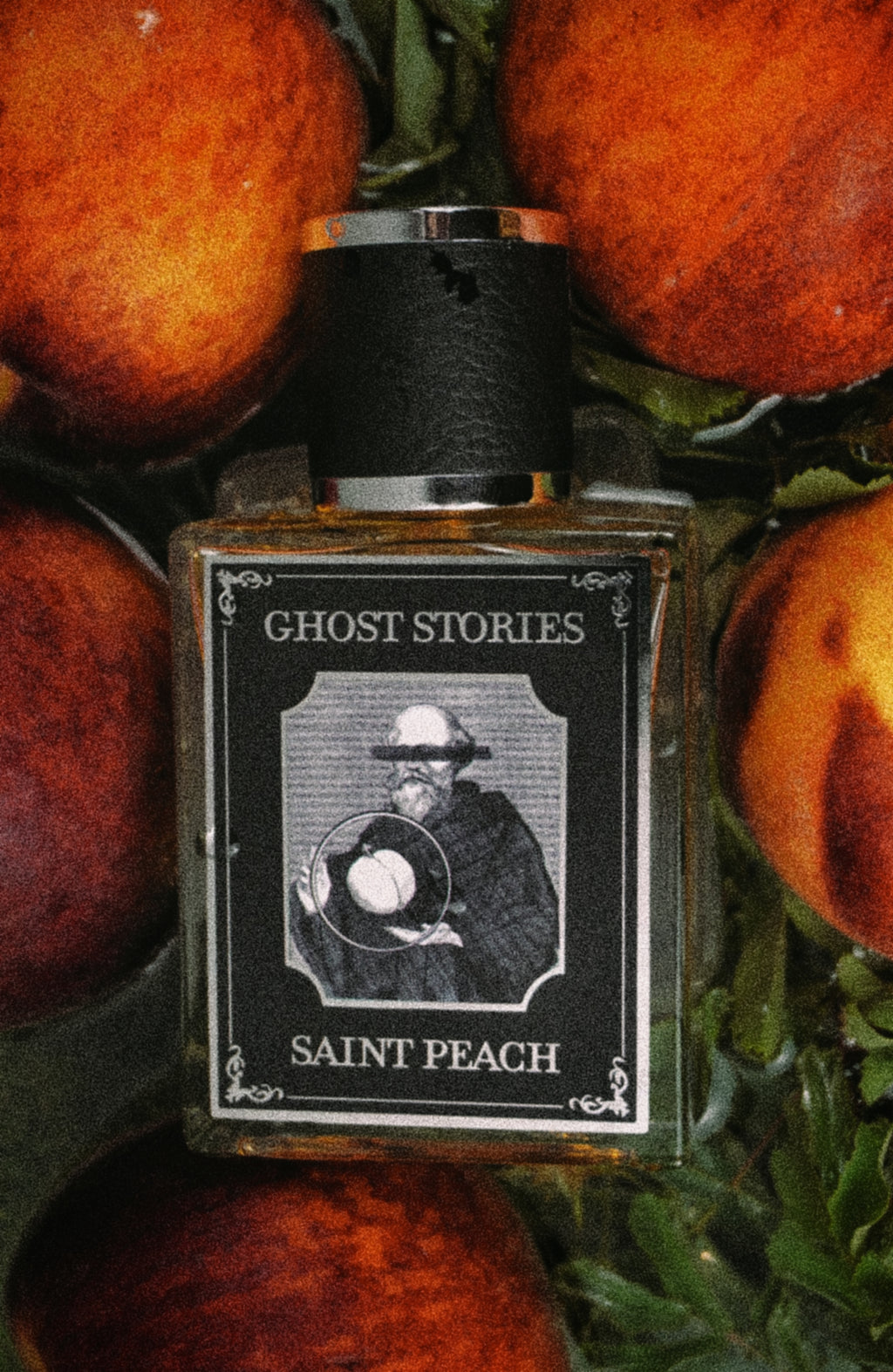Perfume bottle labeled 'Ghost Stories Saint Peach' surrounded by peaches